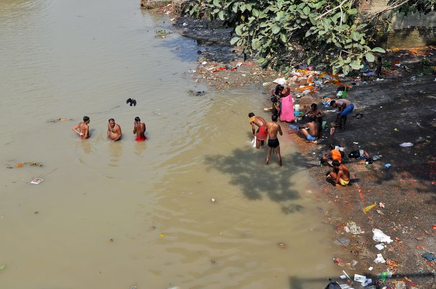 Pessoas nadando em rio de água suja