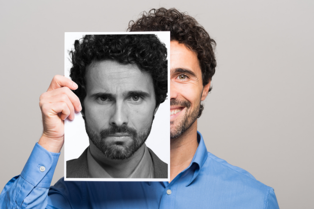Homem mudando de humor segurando um papel com seu rosto bravo na frente da sua expressão feliz
