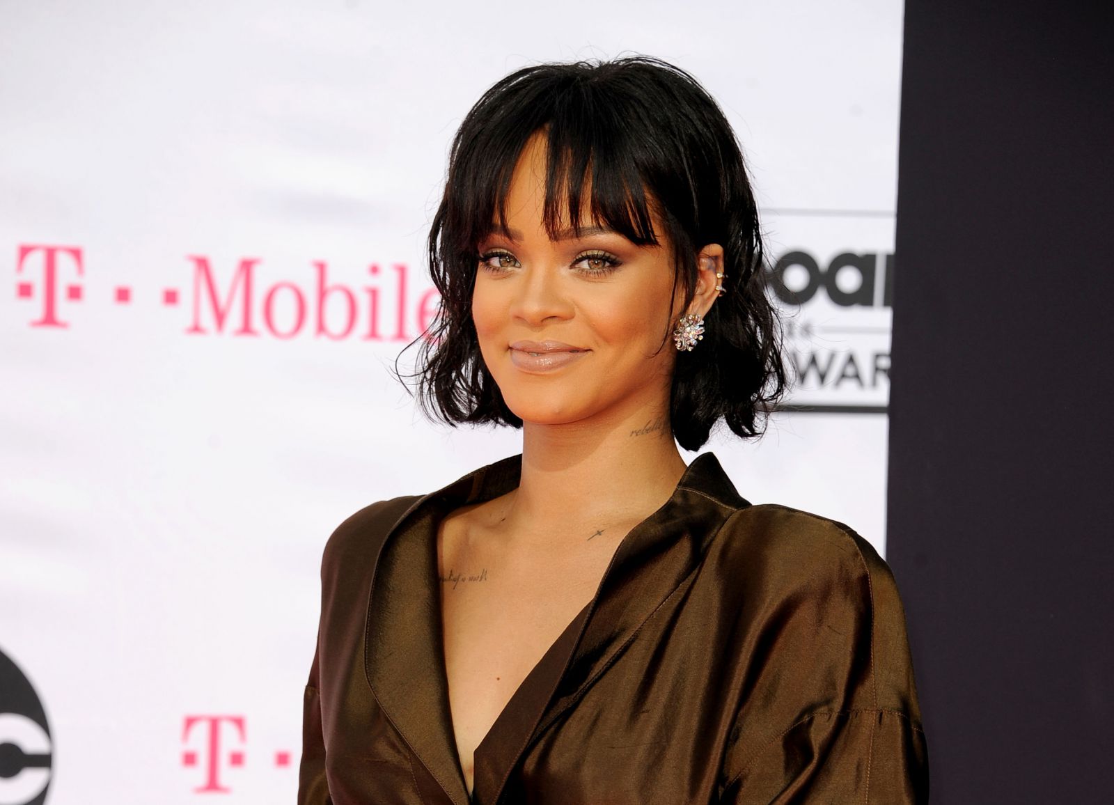 Rihanna olhando para frente sorrindo usando franjinha e cabelo curto