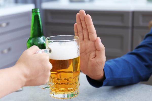Mão recusando um copo de cerveja que está sendo oferecido
