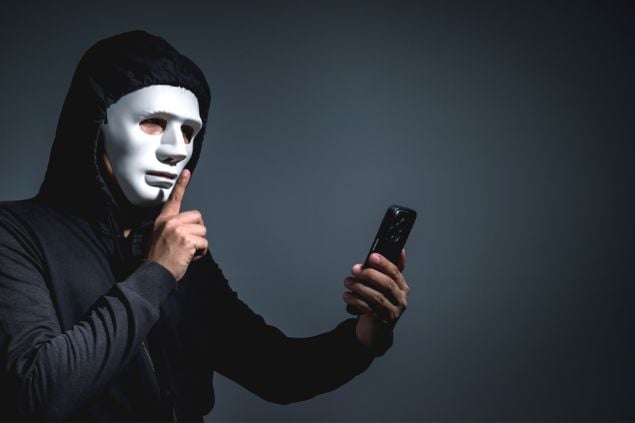 Imagem de um homem mascarado e com um celular roubado na mão