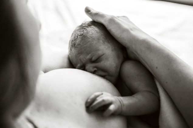 Imagem em preto e branco de uma mãe amamentando um recém-nascido 