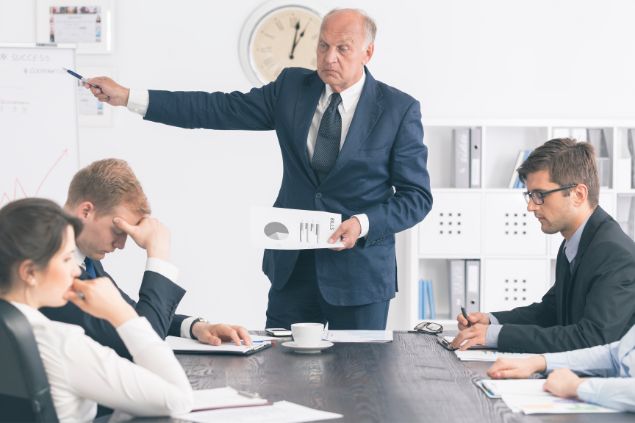 Chefe expondo um de seus funcionários na frente de outros em uma sala de reunião