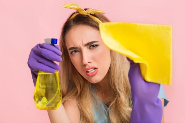 Imagem de uma mulher limpando excessivamente em um fundo rosa, sugerindo perfeccionismo