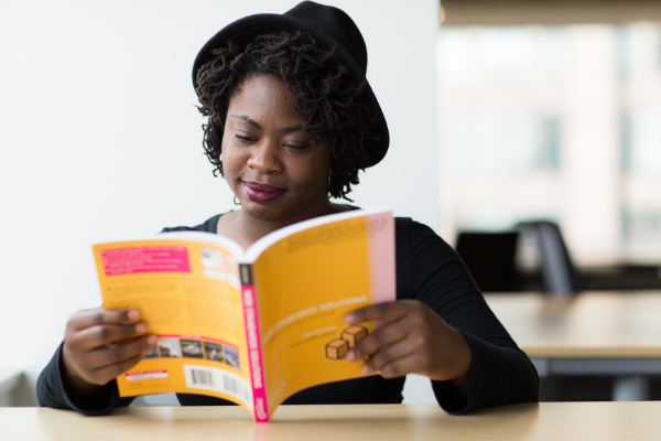 Mulher usando um chapéu preto e lendo um livro