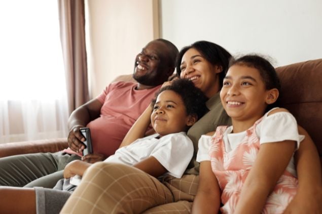Imagem de uma família sorrindo sentada no sofá