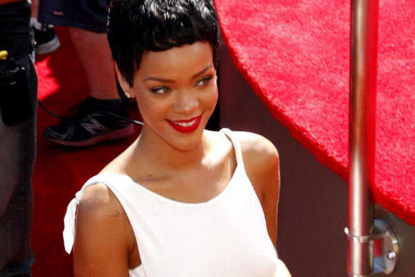 Rihanna sorrindo olhando para o lado ao lado de um palco