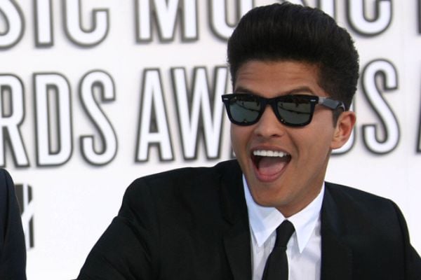 Bruno Mars usando óculos e sorrindo em uma premiação