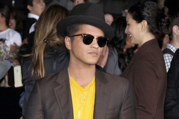 Bruno Mars de óculos escuro e chapéu no meio de pessoas