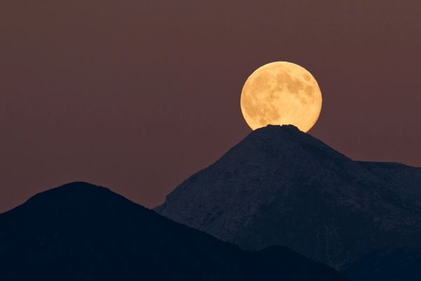 Lua cheia saindo de trás de uma montanha