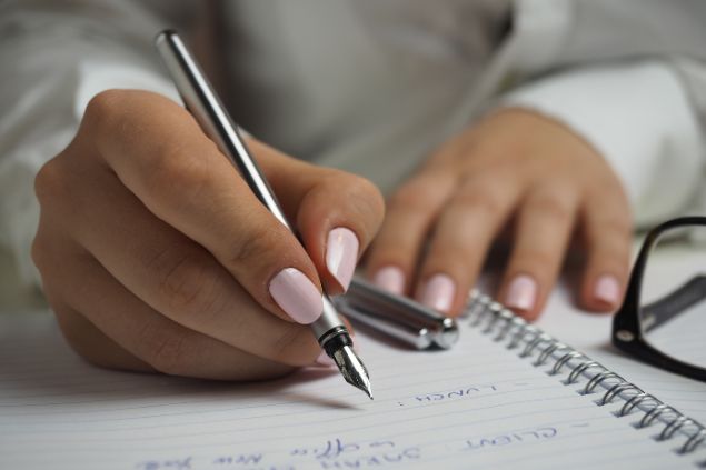 Imagem de uma mulher fazendo listas em um caderno