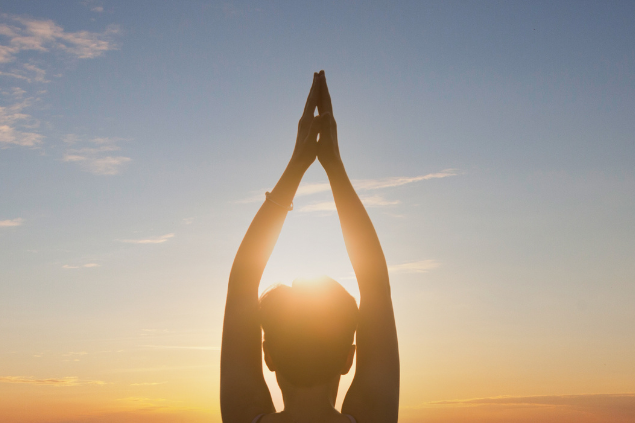 Mulher praticando yoga em pôr do sol
