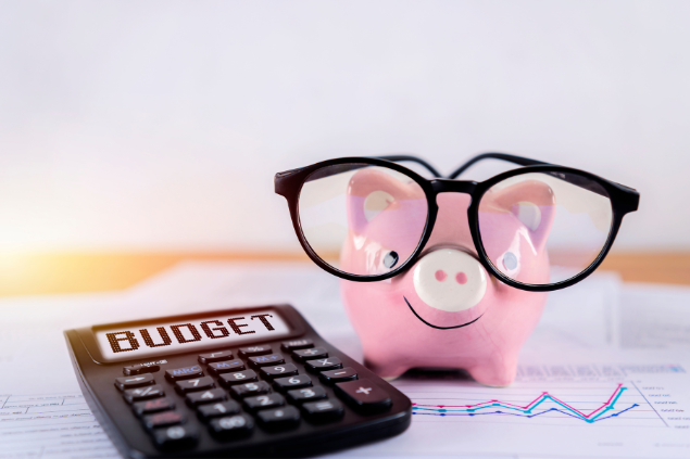 Porquinho de porcelana usando óculos ao lado de uma calculadora