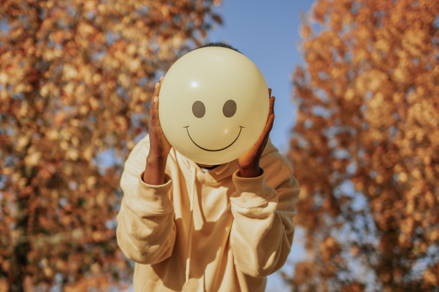 Pessoa segurando um balão com rosto feliz desenhado