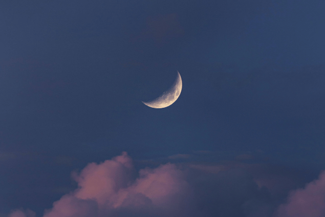 Lua minguante em céu com nuvens rosadas