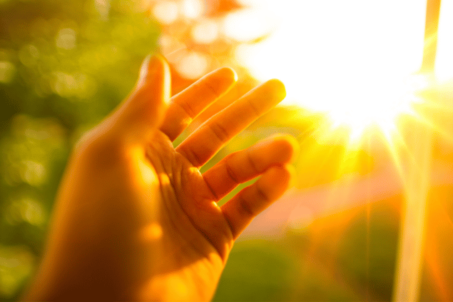 Uma mão apontando em direção a luz do sol