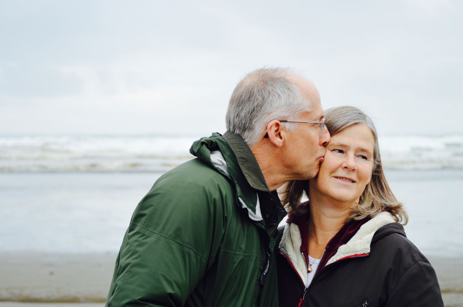 Homem beijando bochecha de mulher em uma praia