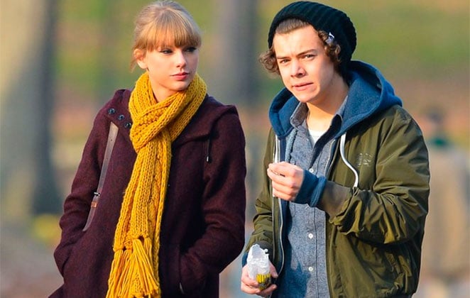 Taylor Swift e Harry Styles com roupas de inverno, passeando em um parque.