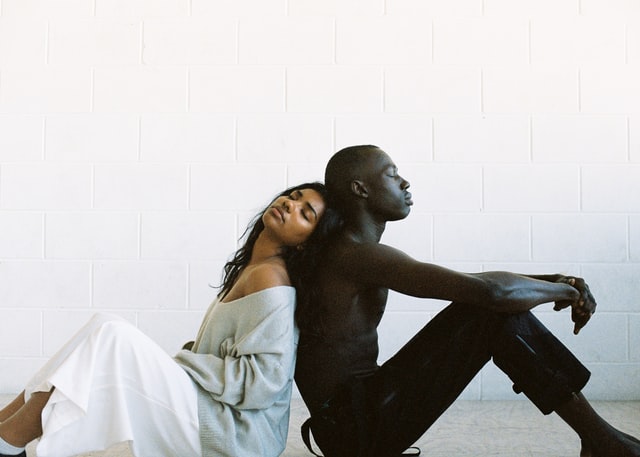 Homem e mulher negros de costas um para o outro.