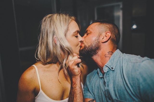 Homem e mulher brancos se beijando.