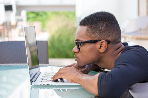 Homem de óculos usando o computador, com expressão concentrada.
