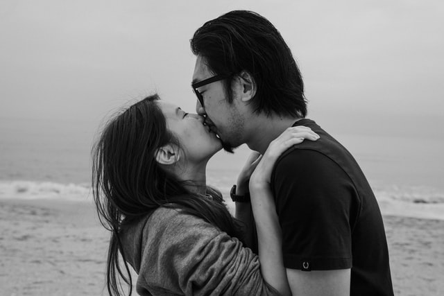 Mulher e homem asiáticos se beijando.