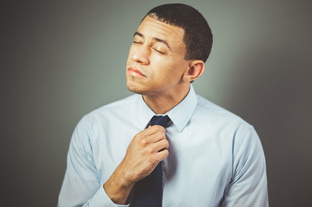 Homem desapertando a gravata com expressão estresse