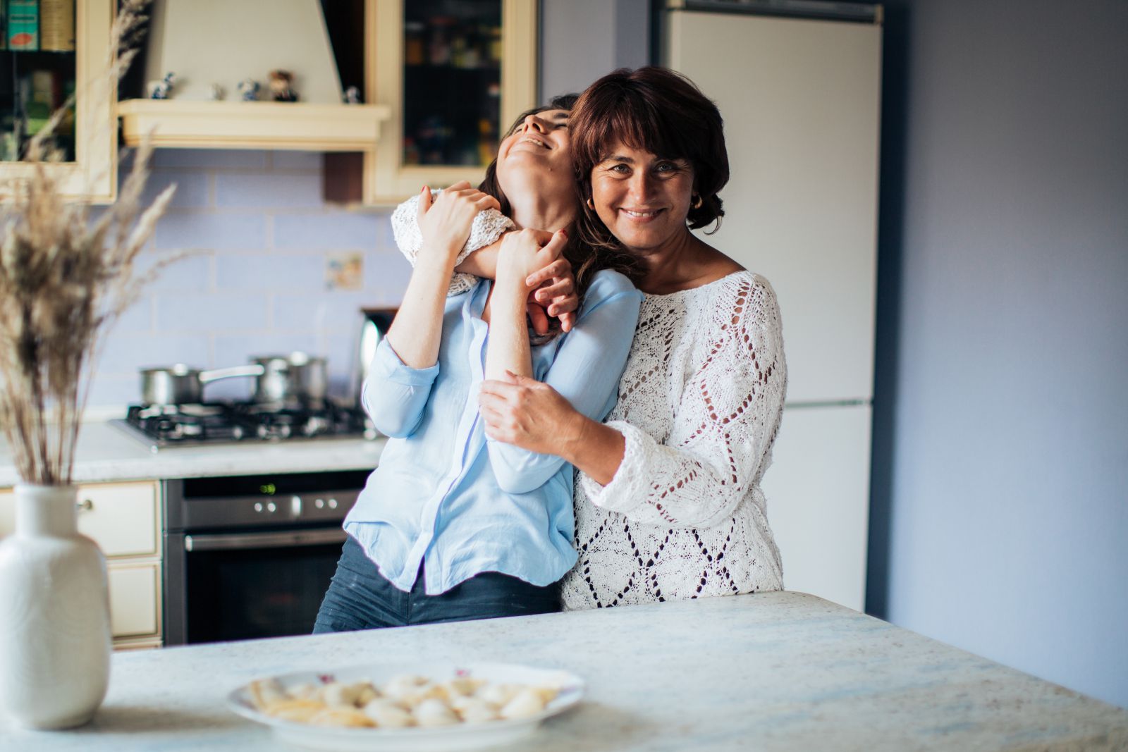 Duas mulheres se abraçando na cozinha