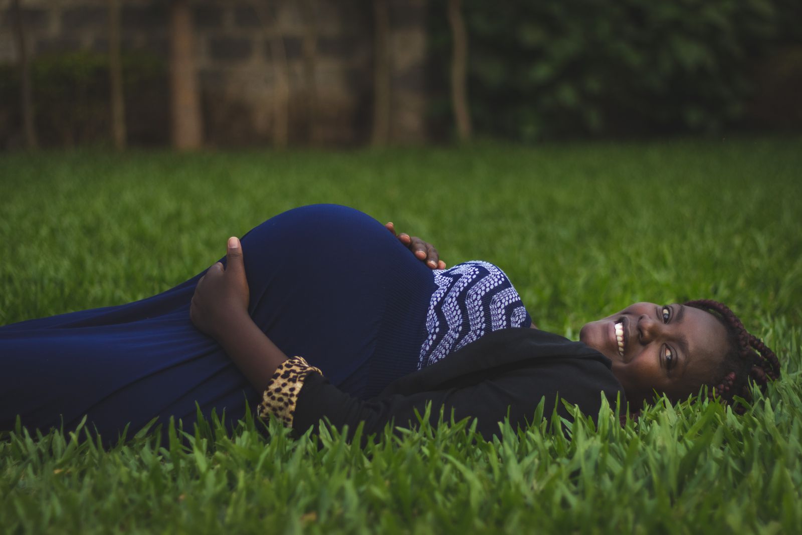 Mulher gravida deitada em gramado 