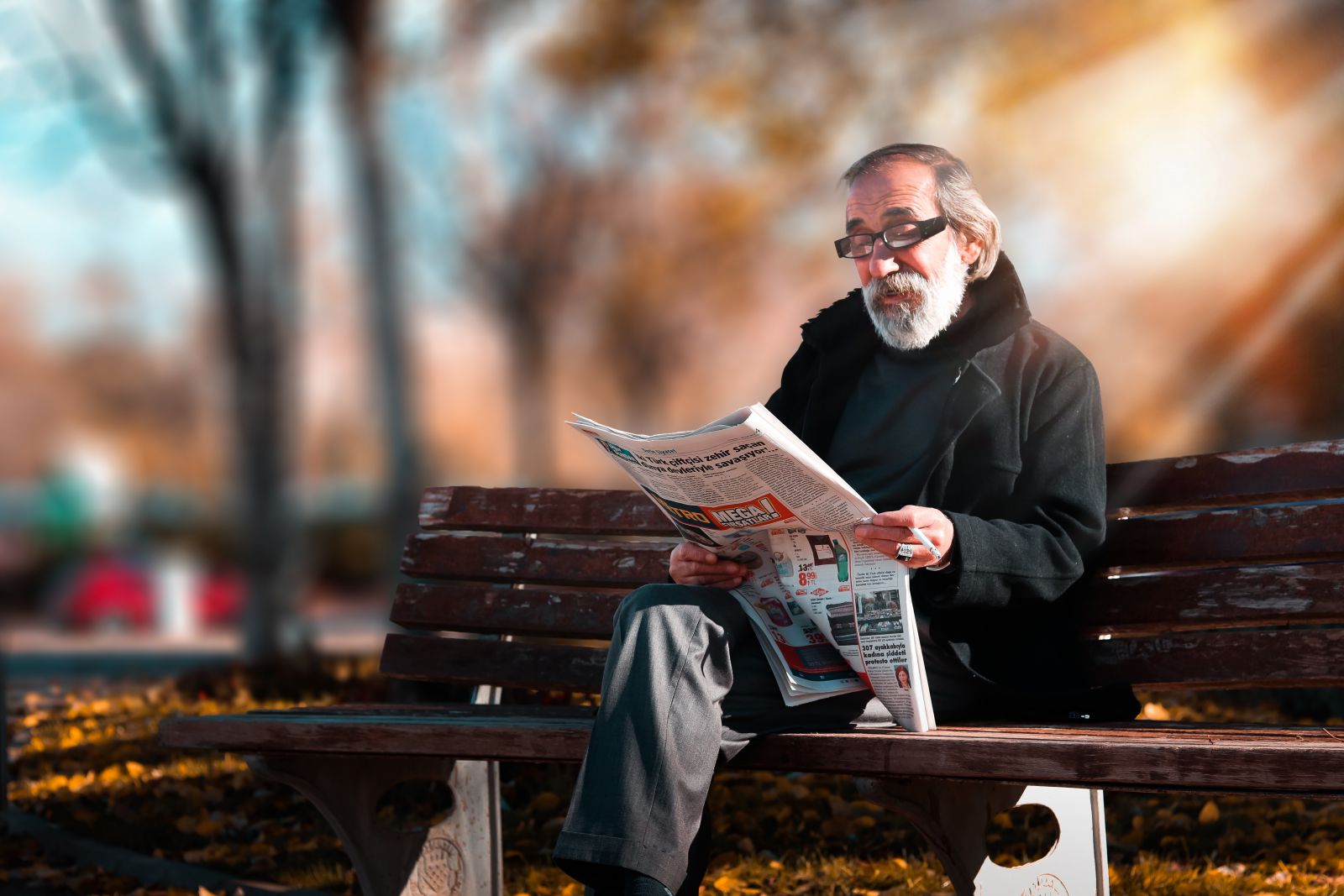 Homem lendo jornal no banco da praça