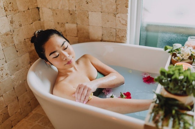 Mulher asiática numa banheira com flores.